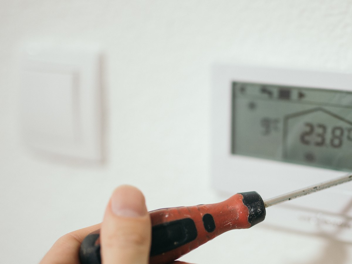 Técnico ajustando termostato durante manutenção preventiva de sistema de climatização